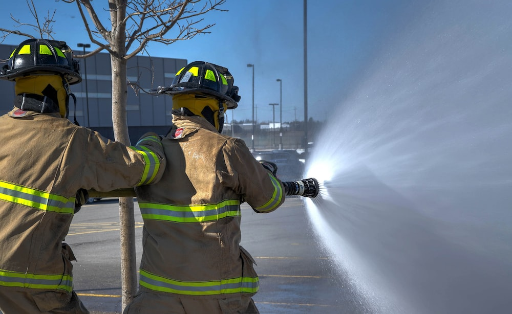 Two firemen with a water hose