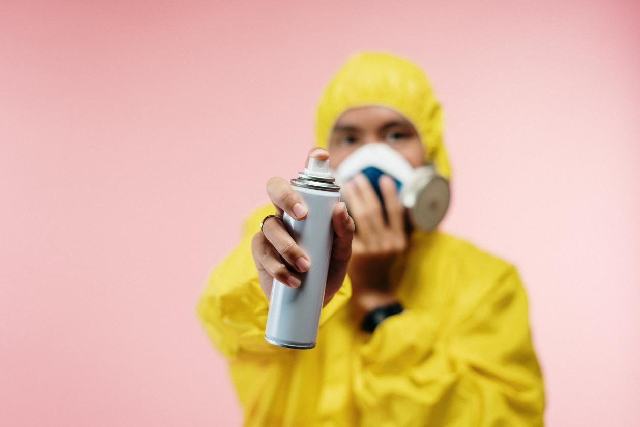 A person wearing a yellow protective suit is holding a spray bottle